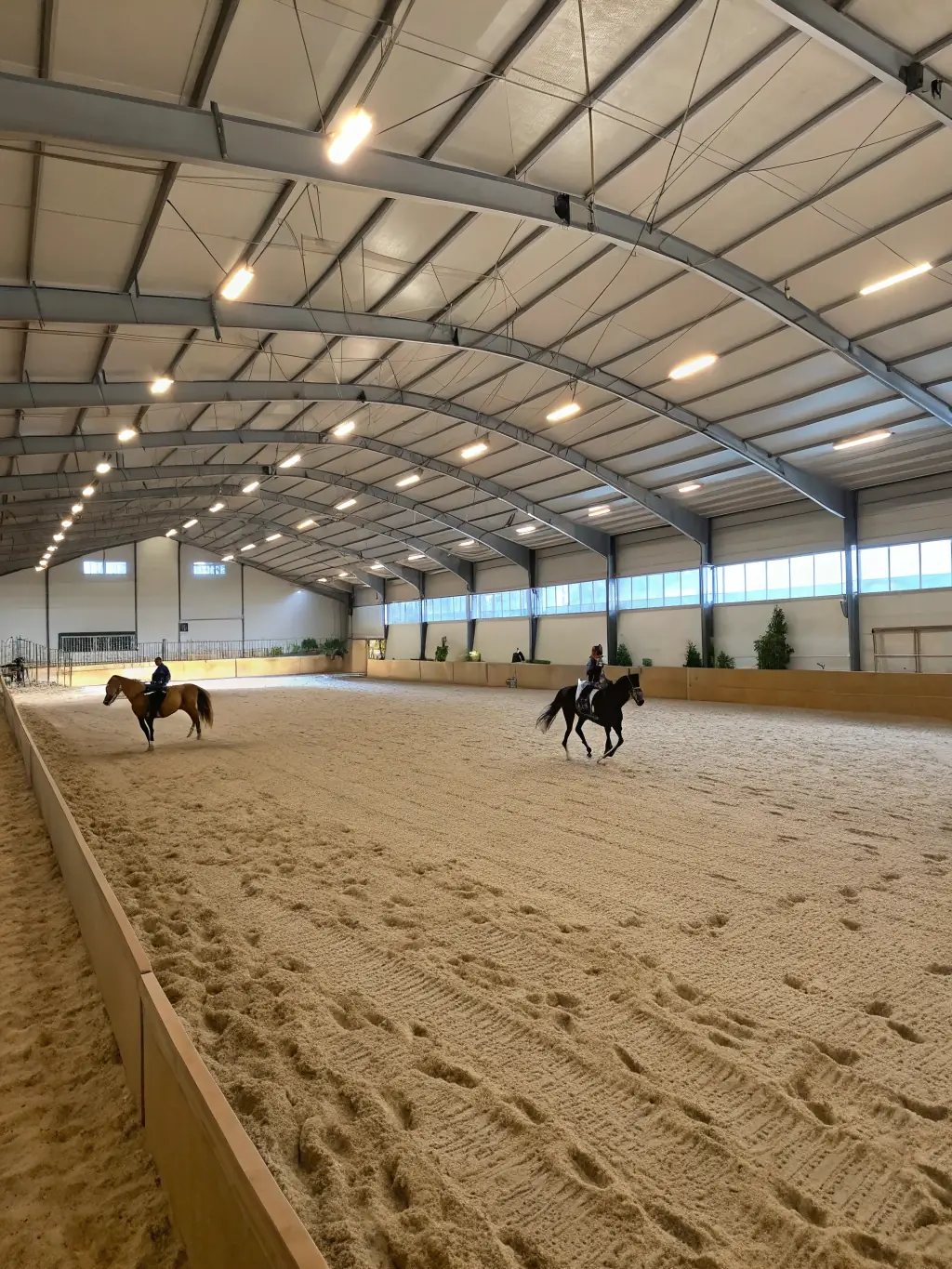 An indoor training facility at RENCONTRES EQUESTRES DE CHAMBERET, featuring a spacious arena with specialized footing, lighting, and climate control for year-round training sessions.